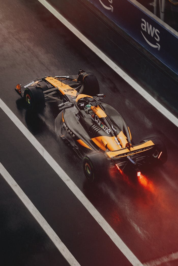 who-we-are Formula 1 car speeding on a wet track during a race, showcasing dynamic motion and sportsmanship.